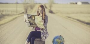 jeune fille assise sur valise avec globe terrestre