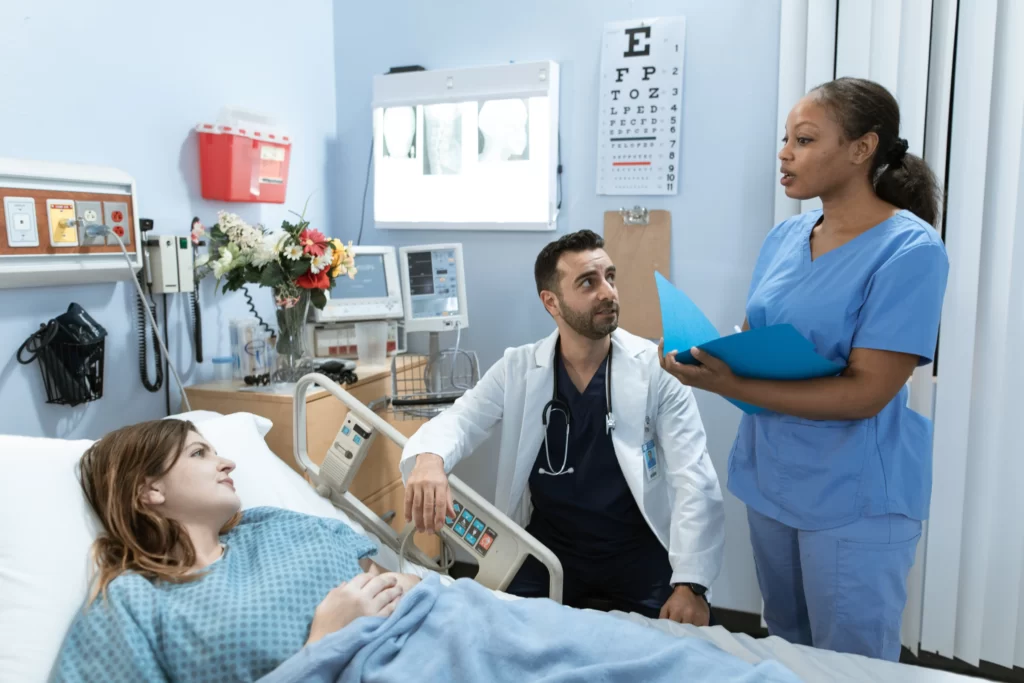femme allongée en boiuse bleue dans un lit d'hôpital avec médecin et infirmière à côté d'elle